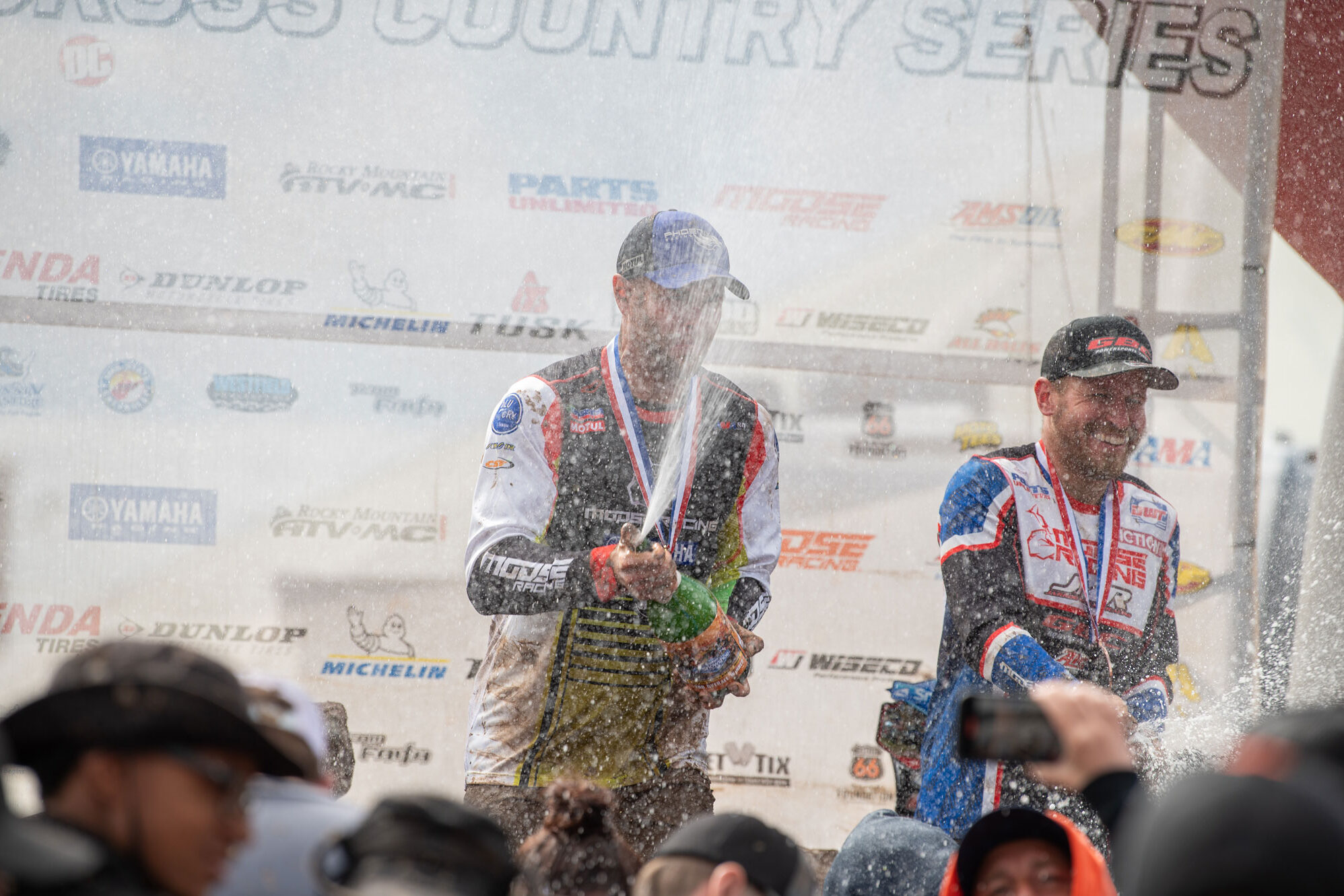 Brycen Neal on the podium spraying champagne in celebration of winning.